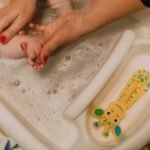 Un parent attentionné baigne doucement son bébé dans une scène de bain moussante, illustrant amour et hygiène.